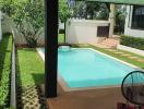 View of a backyard with a swimming pool and garden from a shaded patio