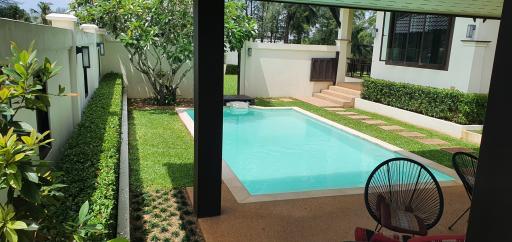 View of a backyard with a swimming pool and garden from a shaded patio