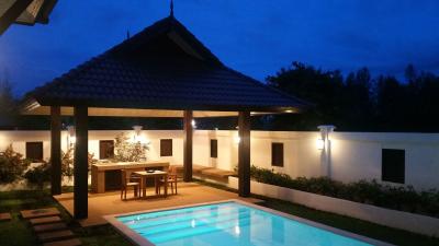 Well-lit private pool with covered dining area during evening