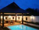 Well-lit private pool with covered dining area during evening