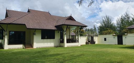 Spacious single-story house with large green lawn and Thai-style roofing