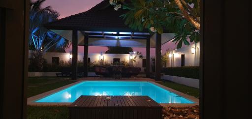 Elegant backyard with a swimming pool and poolside seating area at dusk