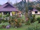 Lush garden with tropical vegetation and detached house under overcast skies