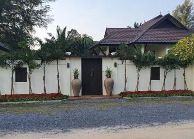 Traditional style gated house with a tiled roof and tropical landscape