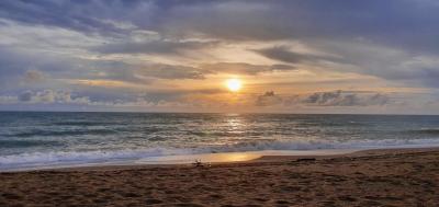 Sunset view from the beachfront showing the ocean, sandy shore, and beautiful sky