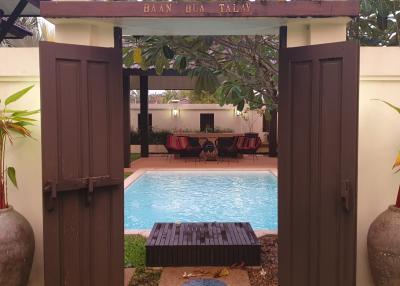 View of a serene pool area with a cozy seating arrangement as seen through an open gate