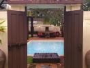 View of a serene pool area with a cozy seating arrangement as seen through an open gate