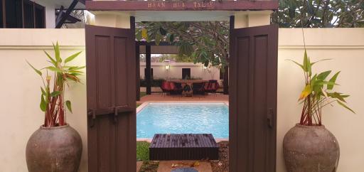 View of a serene pool area with a cozy seating arrangement as seen through an open gate