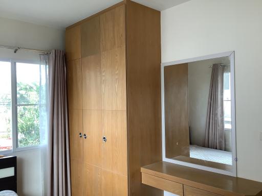 Cozy bedroom with large wooden wardrobe and dressing mirror