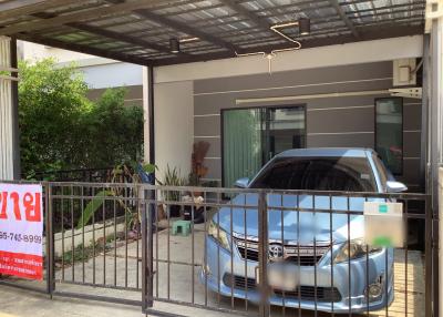 Car parked under the shelter of a modern house with a for sale sign