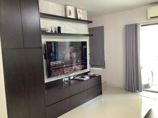 Modern living room interior with large TV screen and ample shelving