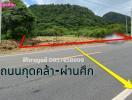 Paved road near a mountainous area with a land plot for sale indicated by arrows and contact information