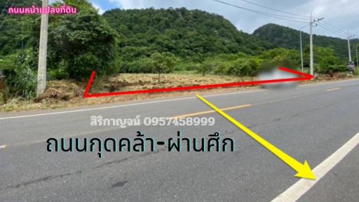 Paved road near a mountainous area with a land plot for sale indicated by arrows and contact information