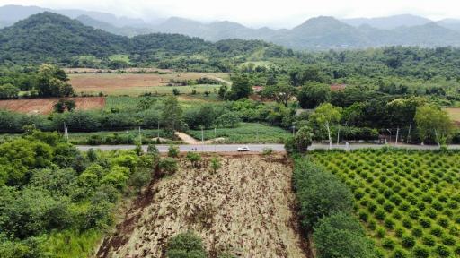 Aerial view of rural landscape with fields, trees, and mountains in the distance