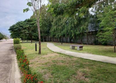 Paved pathway through a leafy outdoor park area with benches
