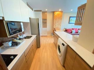 Modern kitchen with wood flooring, stainless steel appliances, and white countertops