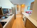 Modern kitchen with wood flooring, stainless steel appliances, and white countertops