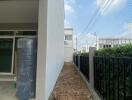 Side yard of a modern home with narrow gardening space and boundary fencing