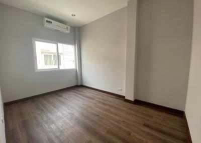 Unfurnished bedroom with natural light from window, hardwood floors, and built-in air conditioning unit