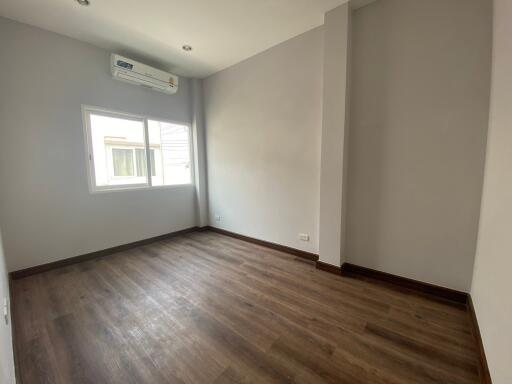 Unfurnished bedroom with natural light from window, hardwood floors, and built-in air conditioning unit