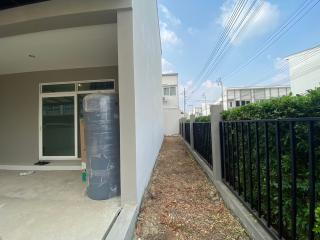 Side exterior view of a modern home with water tank and small garden area