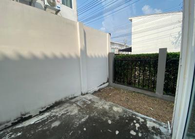 Residential property exterior showing a small yard with a concrete floor and perimeter fencing