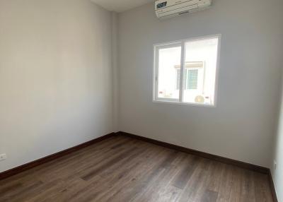 Spacious unfurnished bedroom with wooden flooring and air conditioning unit