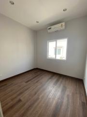 Spacious unfurnished bedroom with wooden flooring and air conditioning unit