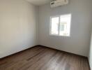 Spacious unfurnished bedroom with wooden flooring and air conditioning unit