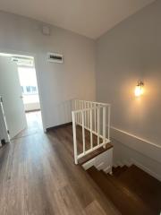 Modern staircase with wooden steps and white railing inside a house