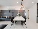 Modern kitchen with adjacent dining space featuring a white dining table, black chairs, and stylish pendant lights