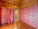 Empty wooden bedroom with red curtains and patterned wallpaper
