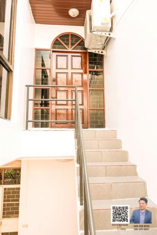 Exterior view of a house entrance with wooden door and stairs