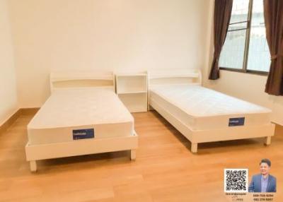Spacious bedroom with two single beds and hardwood flooring