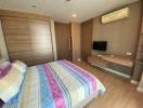 Spacious bedroom with wooden wardrobe and mounted television