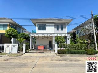 Modern two-story house with a white facade and gated driveway