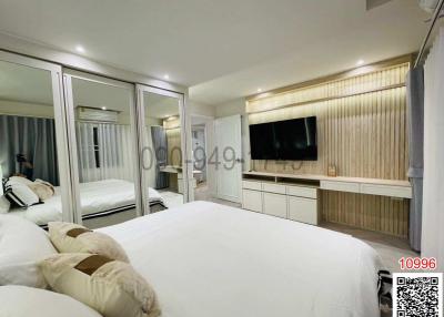 Spacious bedroom with large bed and modern furniture including a mirror wardrobe and television