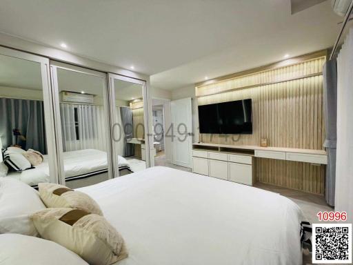 Spacious bedroom with large bed and modern furniture including a mirror wardrobe and television