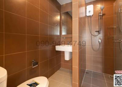 Modern bathroom with wall-mounted sink, glass shower, and brown tile walls