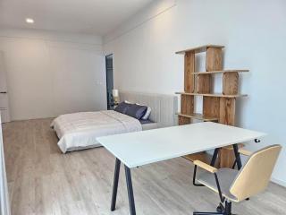 Spacious modern bedroom with a bed, study desk, and wooden bookshelf