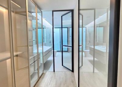 Modern corridor leading to a bedroom with mirrored wardrobe doors and bright lighting