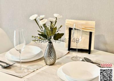 Elegant dining table setup with white plates, wine glasses, and a vase with flowers
