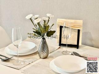Elegant dining table setup with white plates, wine glasses, and a vase with flowers