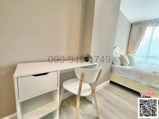 Cozy bedroom with natural light from a large window, featuring a modern white desk and comfortable chair