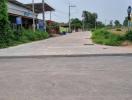 Paved road leading into a residential area with houses and greenery