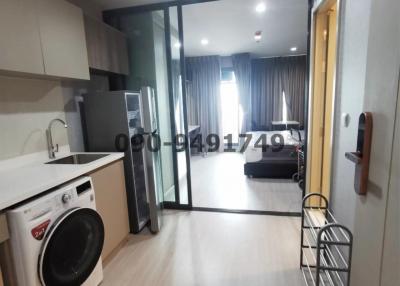 Compact apartment interior with kitchenette, washer, and view into living room area