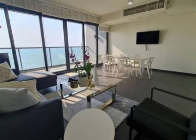 Modern living room with ocean view, comfortable seating, and ample sunlight