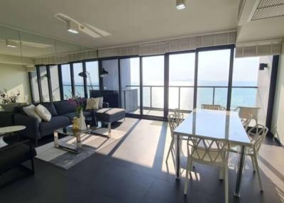 Bright and elegant living room with ocean view, ample seating, and balcony access