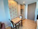 Compact dining space with patterned wallpaper and wood flooring