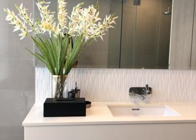 Modern bathroom interior with a sink, mirror, and decorative flowers